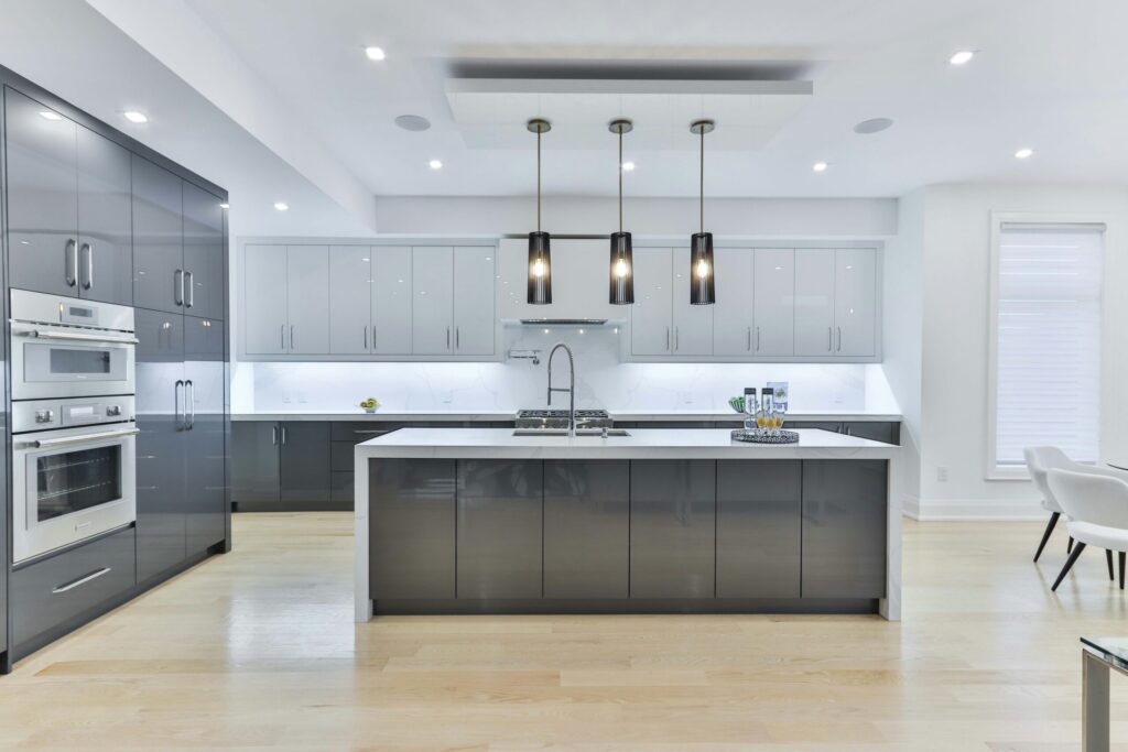 Newly renovated kitchen with gray and white cabinetry and pendant lights hanging above the center island