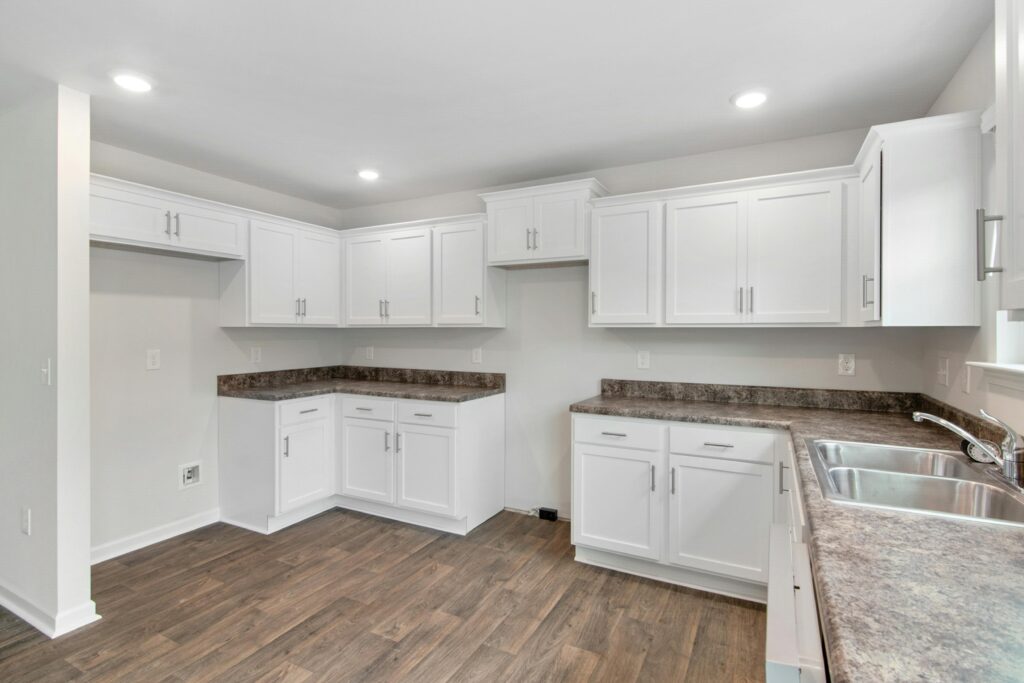 Newly remodeled kitchen with brown granite countertops, white cabinetry, and hardwood floor. The best cleaning services in Lakewood