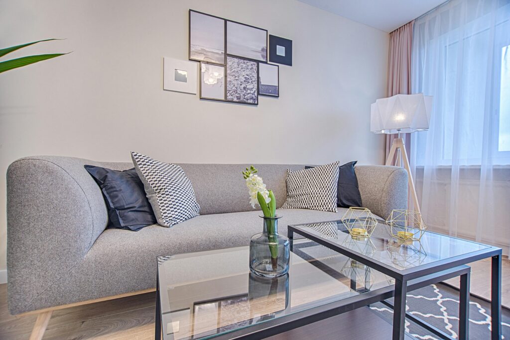 Living room with a gray couch, glass coffee table, and a blue and white rug. The best home cleaning services in Wheat Ridge