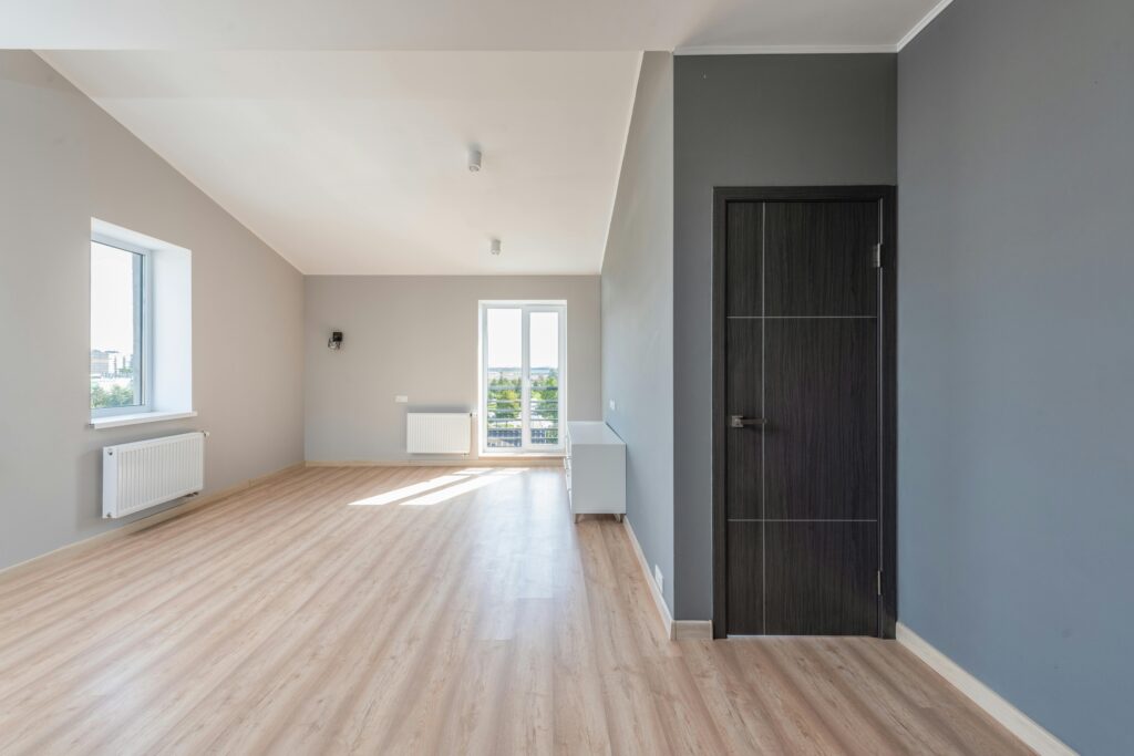 Empty room with spotless hardwood floors and a black door